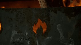 Large firewood burning in a rusty metal brazier, which depicts the symbol of fire. Slow motion. Close-up - Powered by Shutterstock - Get 15% off with code: PIKWIZARD15
