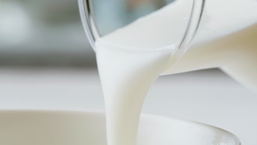 Pouring kefir yogurt into glass cup close-up. Glass with kefir or milk, lactic acid product dairy products concept. Drinking fresh lactose free in morning.