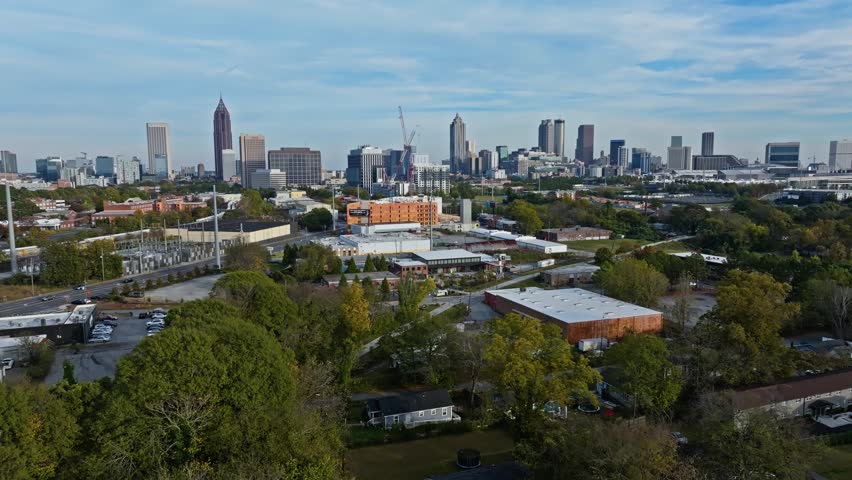 Aerial backwards shot of suburbia with homes and houses in District. Skyline with skyscrapers of Atlanta, Georgia in distance. Wide shot.