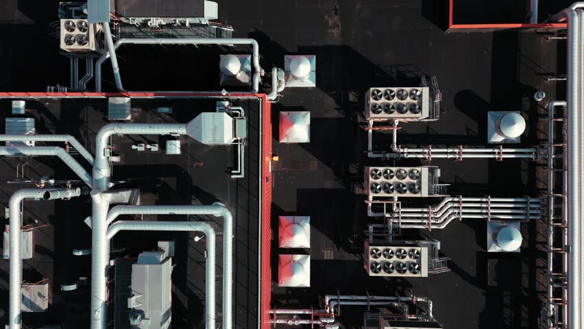 Aerial close-up of complex HVAC piping system on rooftop, showing intricate network of metal pipes, top down pan as fans spin