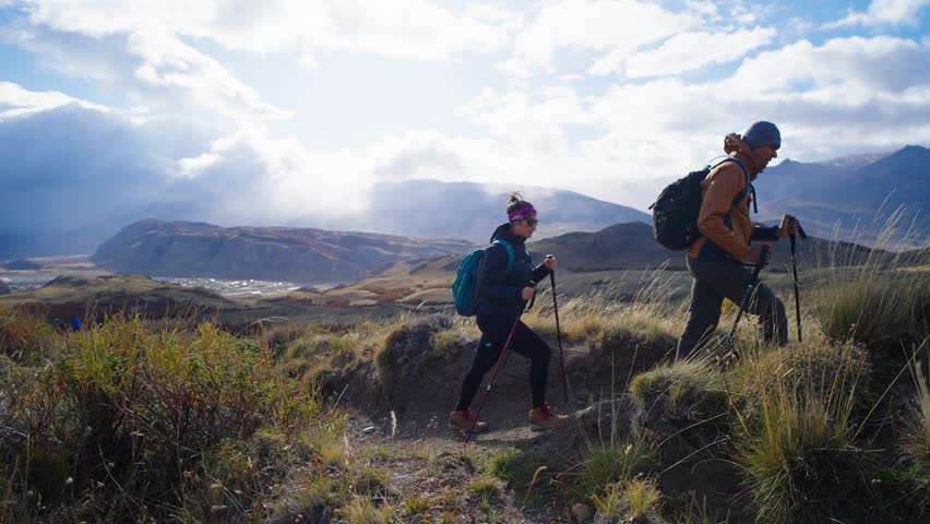 Young couple hiking, trekking in mountains with backpacks, enjoying their adventure - tourism concept at El Chantel Argentinean Patagonia
