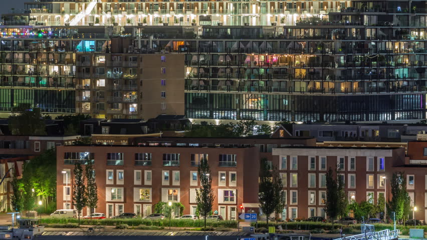 Aerial timelapse of Katendrecht peninsula at night and Maashaven harbour in Rotterdam, Netherlands. Illuminated city skyline, modern buildings glowing windows and traditional Dutch waterfront houses