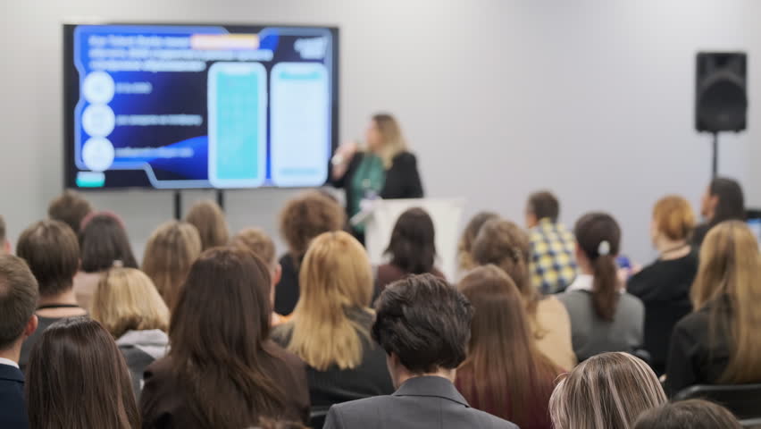 People in a conference room attentively listening to a technology presentation on a screen.