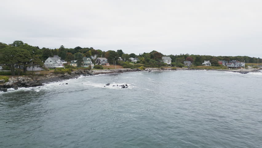 Coastal view of Peaks Island near Portland, Maine with houses, rocks, and calm ocean waves