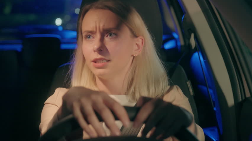 Nervous worried stressed Caucasian woman female girl automobile driver stopped by police emergency light siren steering wheel alcohol drunk driving traffic accident arrest inside car auto night late