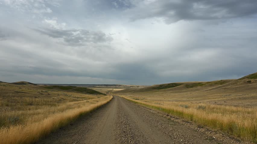 Jiggling footage as camera bounces while driving along dirt road through fall badlands

