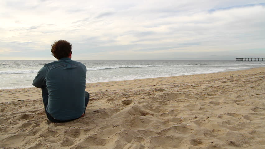 Man sits watching the Pacific Ocean on the California coast. Hermosa Beach Pier