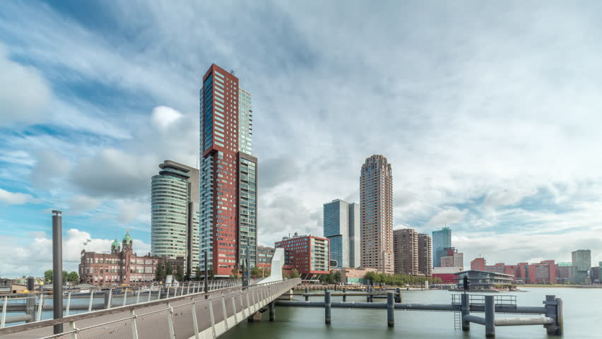 Hyperlapse of the Rijnhaven Bridge, known locally as Hoerenloper, in Rotterdam, Netherlands. A pedestrian and bicycle bridge with modern skyscrapers and cloudy skies in the background timelapse