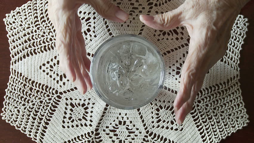 Elderly woman's hands, crippled with arthritis, pick up a glass of iced water to