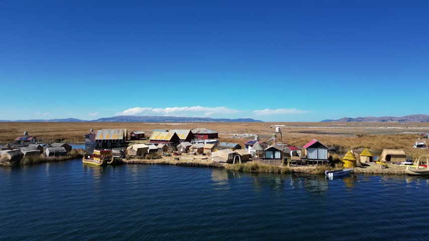 Drone footage of Lake Titicaca, Peru, showcasing floating villages, traditional boats, huts, islands, and theAndes mountains in the background. Perfect for scenic and cultural visuals.