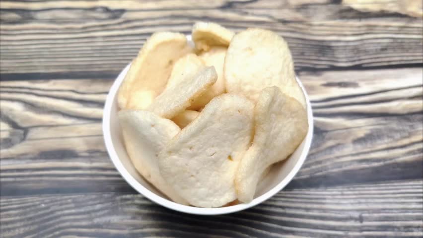 A pile of shrimp crackers in a small bowl. Shrimp crackers are made from a mixture of tapioca flour and finely pounded shrimp with spices and flavor enhancers. A snack from Sidoarjo, Indonesia.