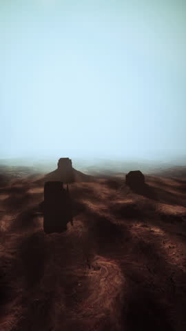 A cluster of rocks in the heart of a barren desert landscape under the scorching sun.