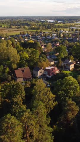 Sunlit suburban neighborhood with houses and lush trees captured from an elevated angle in late afternoon