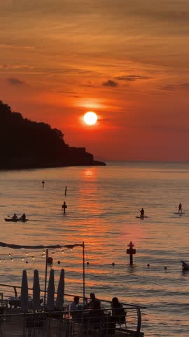a group of people eating others paddleboarding at sunset on the amalfi coast
