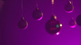 Christmas tree golden silver green balls highlighted by neon light hanging from top, glittering ornaments garland close shot on purple festive background. - Powered by Shutterstock - Get 15% off with code: PIKWIZARD15