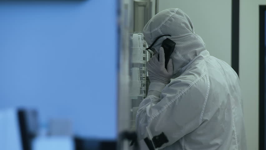 Technician in full-body coveralls deals with a phone call during the