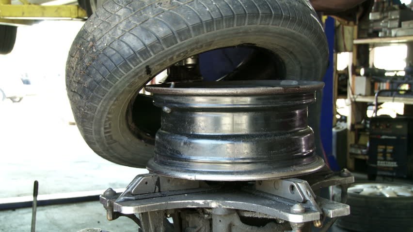 Car tire being put onto wheel rim in auto repair shop.