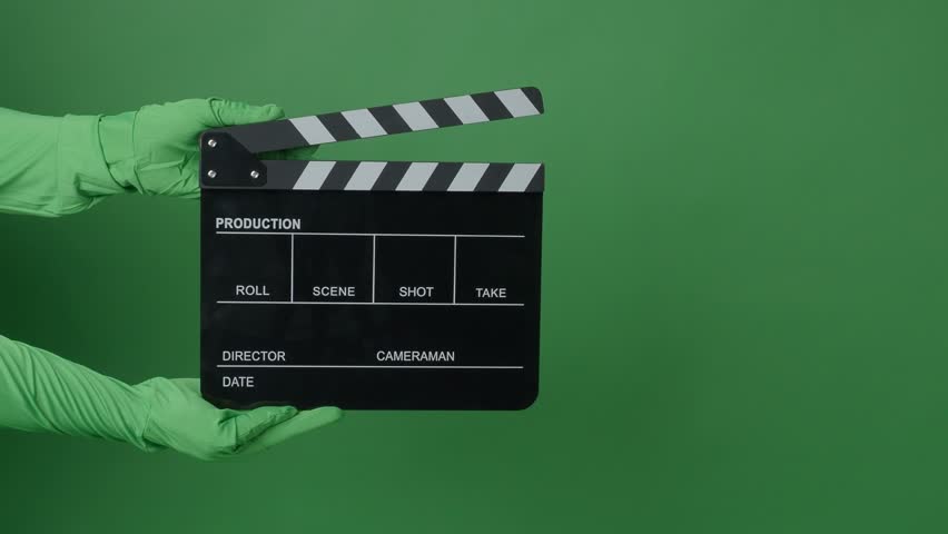 Movie Clapper board clapped by Hands on green screen camera background. Filmmaker hit film slate on green camera frame. Clapperboard Chroma key suit shooting. Green screen composite video production.