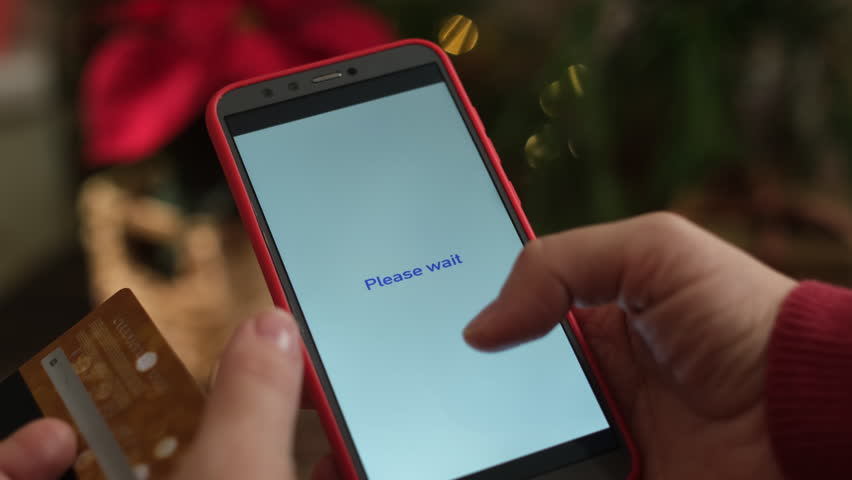 Female hands holding smartphone and credit card to pay for Christmas shopping online