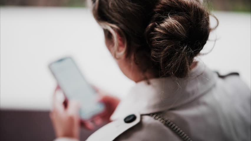 Blurry view of a brunette woman typing on her phone