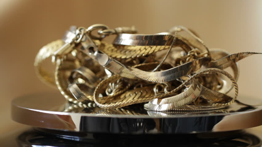 Gold jewelry placed on scales with a gold backdrop. Shallow focus with camera