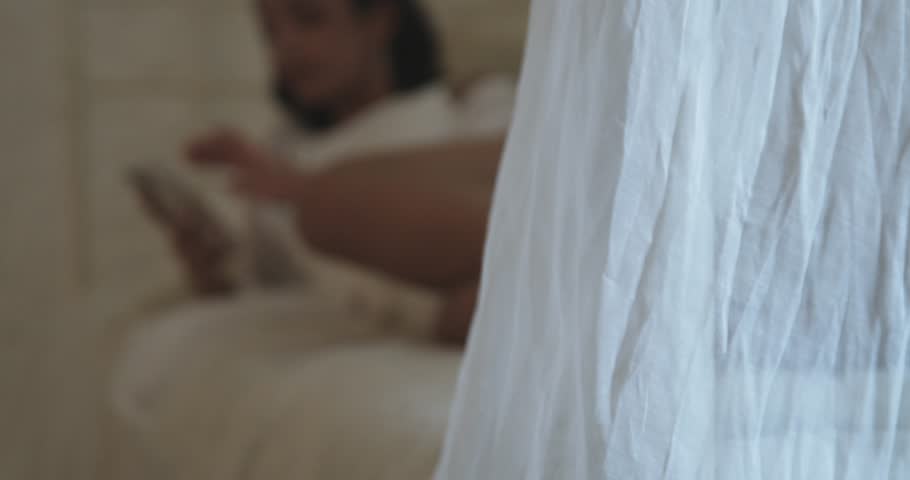 Young woman lying on a bed with cell phone in hand with bookeh
