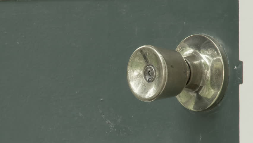 Hand reaches in, turns a brass handle and opens a green door. 