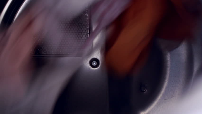 Tight shot of clothes going around in a tumble drying. Looping clip.