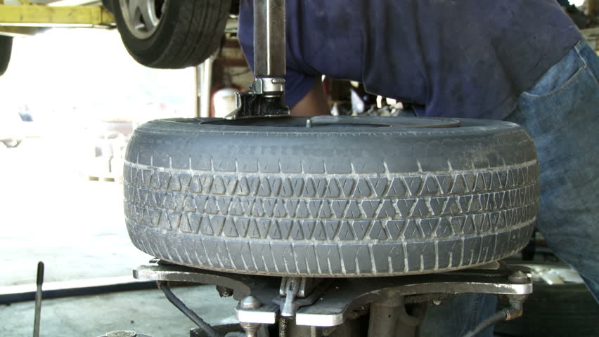 Car tire being removed from rim in auto repair shop.