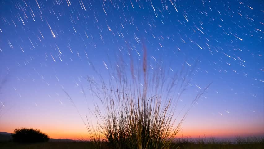 Timelapse of moving star trails in night sky. The Milky Way galaxy rotating over the mountain range in summer time
