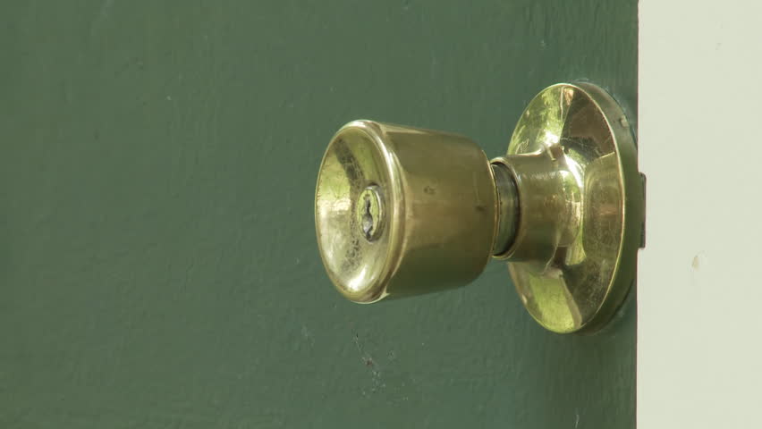 Hand reaches down and, from below, turns a brass handle and opens a green door.