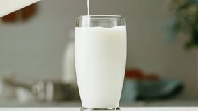 Milk pouring in glass cup close-up. Glass with yogurt, dairy products concept. Drinking fresh lactose-free milk in morning. - Powered by Shutterstock - Get 15% off with code: PIKWIZARD15