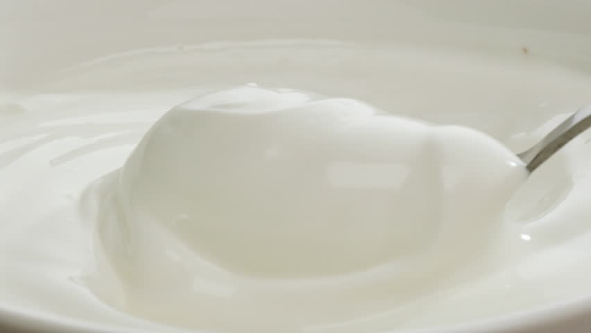 Pouring kefir yogurt into glass cup close-up. Glass with kefir or milk, lactic acid product dairy products concept. Drinking fresh lactose free in morning.