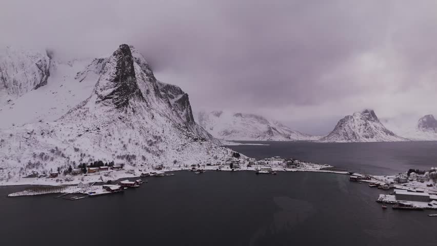 Flying towards big mountains at Reine, Lofoten, Norway on a winter day with lots of clouds