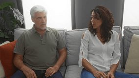 Middle-aged couple having a serious discussion on a sofa in a cozy living room, showcasing their relationship dynamics in a home setting. - Powered by Shutterstock - Get 15% off with code: PIKWIZARD15