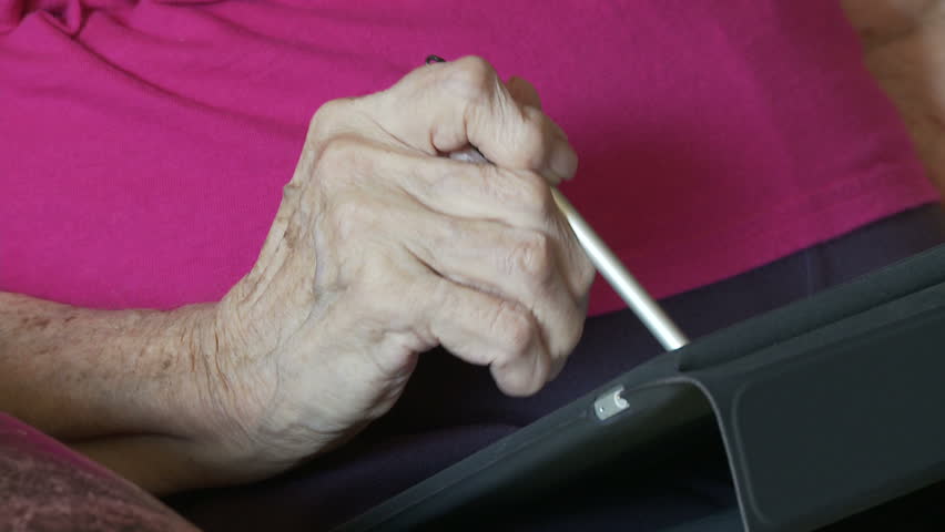 Elderly woman's hands, crippled with arthritis, use a touch-screen tablet
