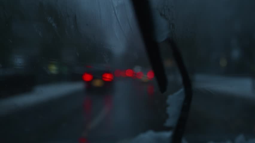 Cars and other vehicles in busy city traffic on a snowy evening, 4K with selective focus