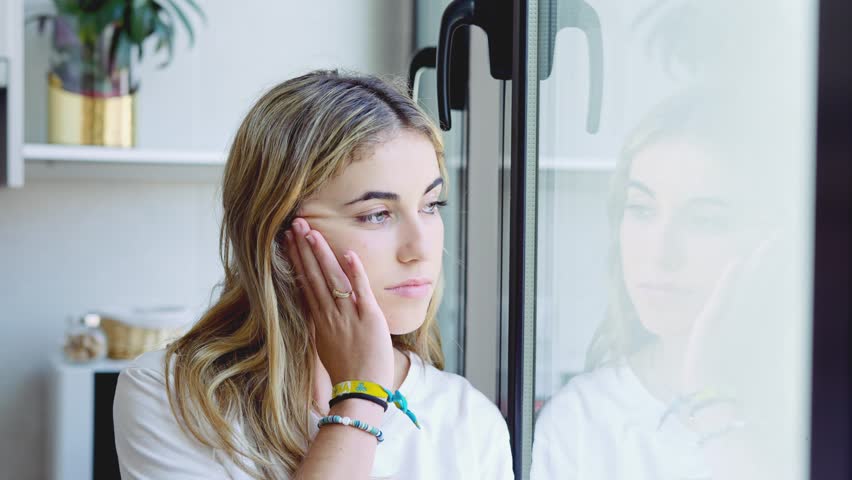 Unhappy thoughts. Worried young caucasian woman look at window feel lonely sad wait for boyfriend coming back after quarrel. Pessimistic millennial lady hide from life problems at home. Copy space
