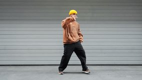 Active male dancer expressive dance move on outdoor concrete steps wearing brown hoodie performs  against modern building. Dynamic posture urban setting showcase energy street dance culture. Freedom - Powered by Shutterstock - Get 15% off with code: PIKWIZARD15