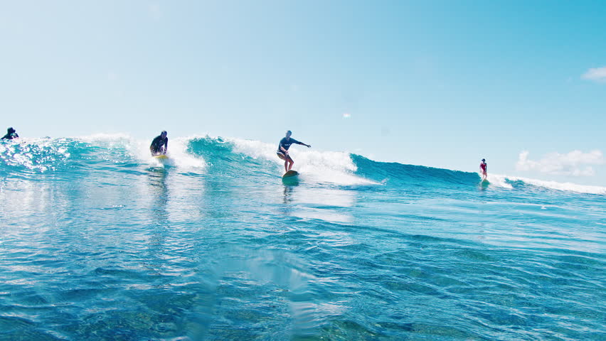 Two surfers sharing and riding waves on their surfboards in the ocean. Surfing etiquette violation. Maldives
