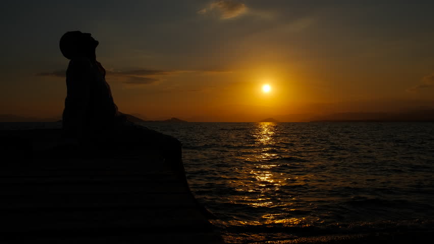 Man feel lonely on pier. A silhouette of man feeling sorrow because of his loneliness on the wooden pier by the evening sea.