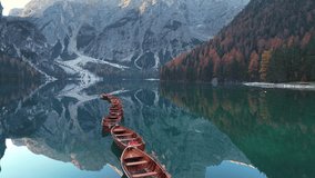 Wooden rowboats aligned in a calm lake surrounded by mountains and autumn trees at dawn - Powered by Shutterstock - Get 15% off with code: PIKWIZARD15