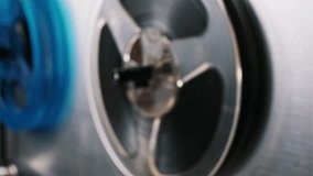 Detailed view of a vintage reel-to-reel tape machine with a blue transparent reel rotating. The mechanical elements are highlighted, providing a captivating visual. Retro or technical - Powered by Shutterstock - Get 15% off with code: PIKWIZARD15
