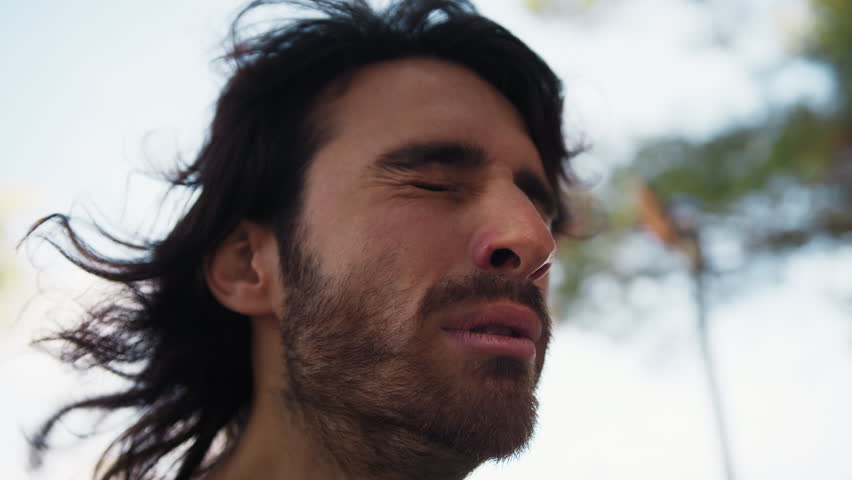 Long Hair Man Chews Sour Lemon and Makes Disgusted Facial Expressions Outdoors