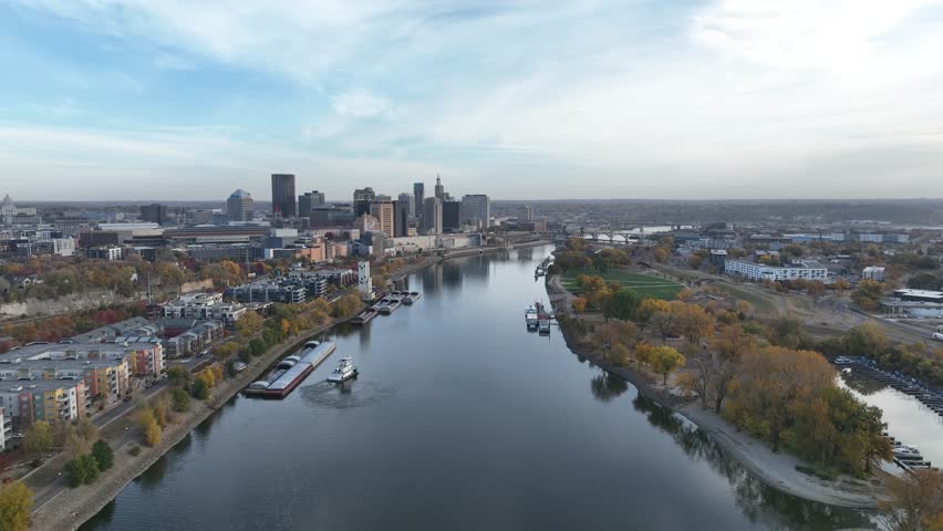 Aerial footage of a tugboat on the Mississippi River approaching the St. Paul, Minnesota skyline on a fall day