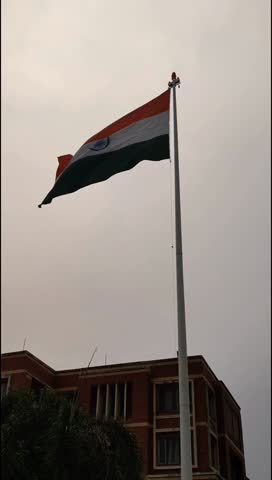 India flag flying high at Connaught Place with pride in blue sky, India flag fluttering, Indian Flag on Independence Day and Republic Day of India, tilt up shot, Waving Indian flag, Har Ghar Tiranga