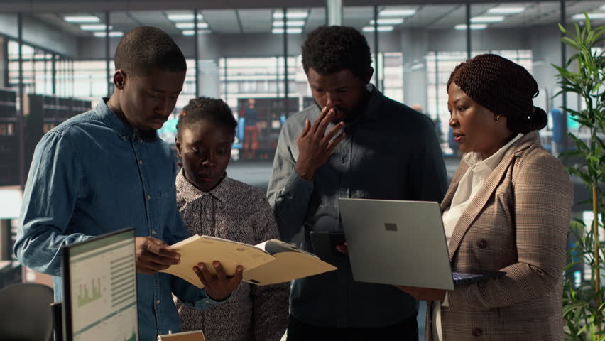 Staff members and leader analyzing financial data in order to create a new balance report, dealing with the annual paperwork to ensure a useful resource allocation for business success. Camera A.