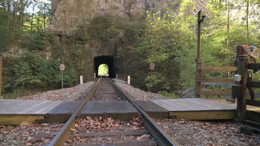 Mother carrying her child in backpack crosses railroad tracks near historic tunnel at Natural Tunnel State Park in Virginia, USA, Mother carrying her child in backpack crosses railroad tracks