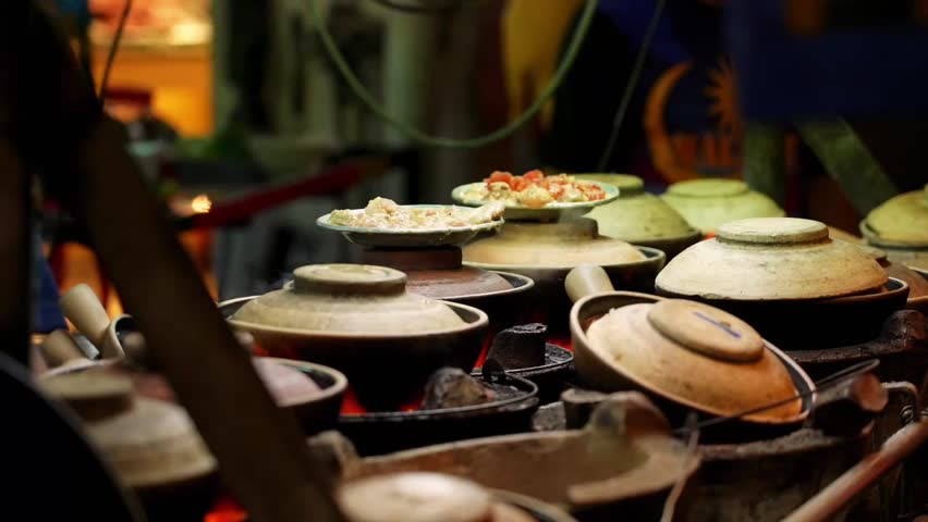 30 fps video of human hand preparing, cooking a clay pot rice bowl at Petaling night street food market, Kuala Lumpur, Malaysia