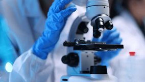 Scientist wearing a lab coat and gloves is adjusting a microscope in a laboratory. - Powered by Shutterstock - Get 15% off with code: PIKWIZARD15